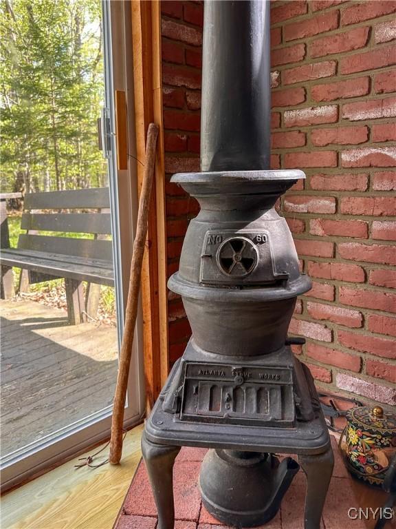 123 Mohawk Dr W, Webb, NY 13420 - detailed view of a wood stove, wood finished floors, and brick wall