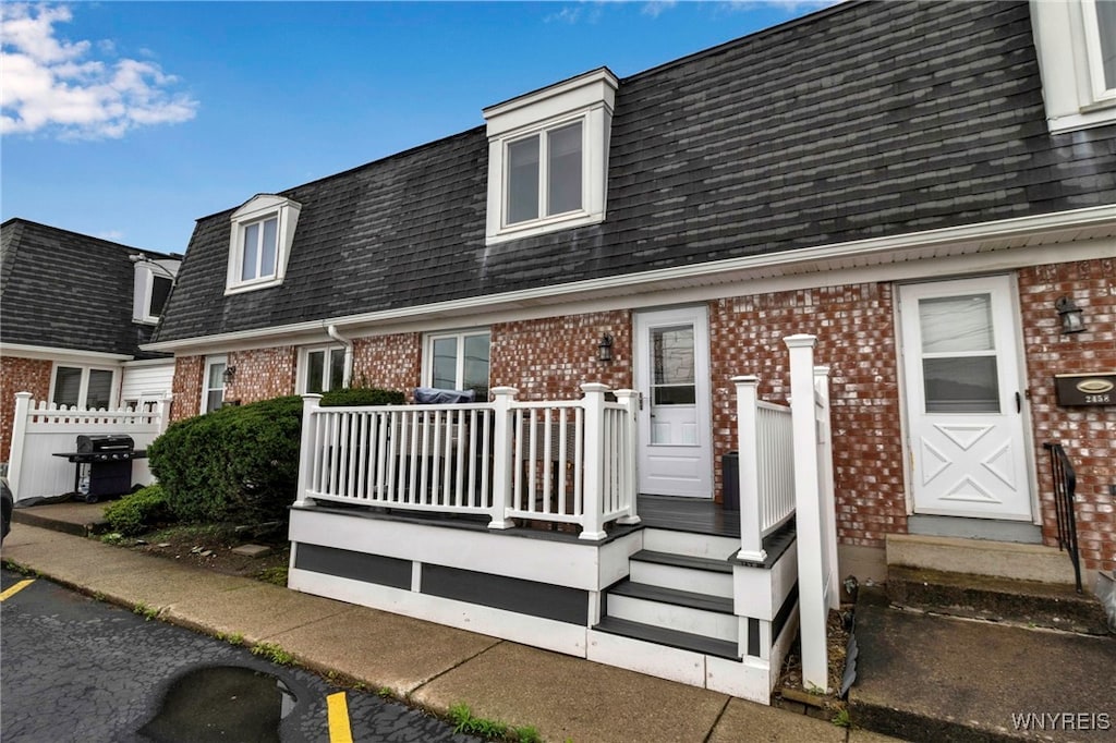 2462 Colvin Blvd, Tonawanda-Town, NY 14150 - view of front of home with brick siding, a shingled roof, a deck, mansard roof, and fence