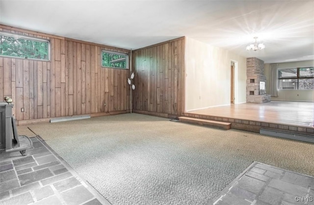 115 Stafford Dr, Rutland, NY 13612 - unfurnished living room with wood walls, a chandelier, a wood stove, and a fireplace