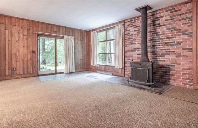 115 Stafford Dr, Rutland, NY 13612 - unfurnished living room featuring a wood stove, carpet floors, plenty of natural light, and wood walls
