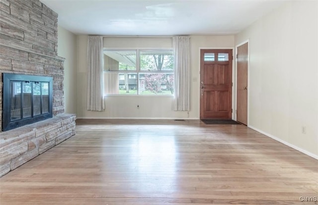 115 Stafford Dr, Rutland, NY 13612 - unfurnished living room featuring wood finished floors, a stone fireplace, and baseboards