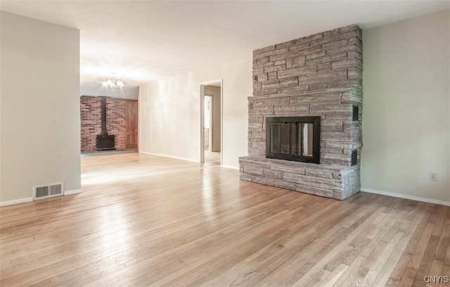 115 Stafford Dr, Rutland, NY 13612 - unfurnished living room with a wood stove, wood finished floors, a chandelier, and a fireplace