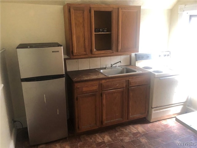 515 9th St, Niagara Falls, NY 14301 - kitchen with freestanding refrigerator, a sink, washer / dryer, brown cabinetry, and dark countertops