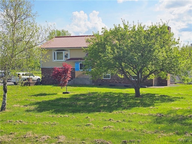 5813 Grace Rd, Deerfield, NY 13502 - view of front of home featuring a tiled roof, stucco siding, a front lawn, and brick siding