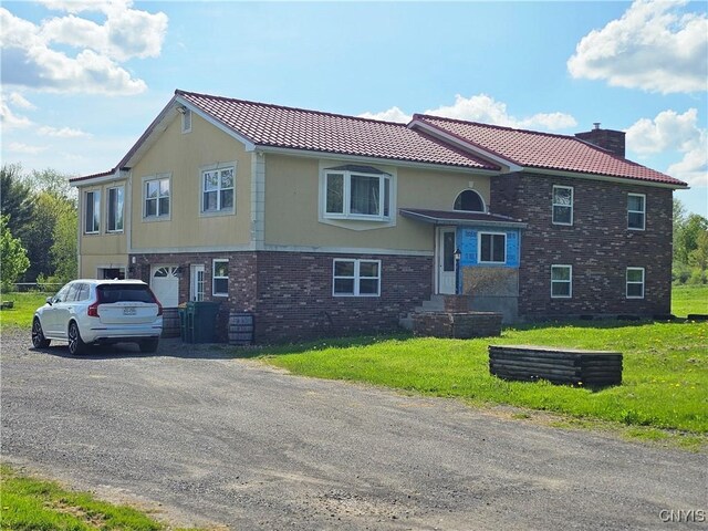 5813 Grace Rd, Deerfield, NY 13502 - view of front of property with brick siding, a chimney, a front lawn, and a tiled roof