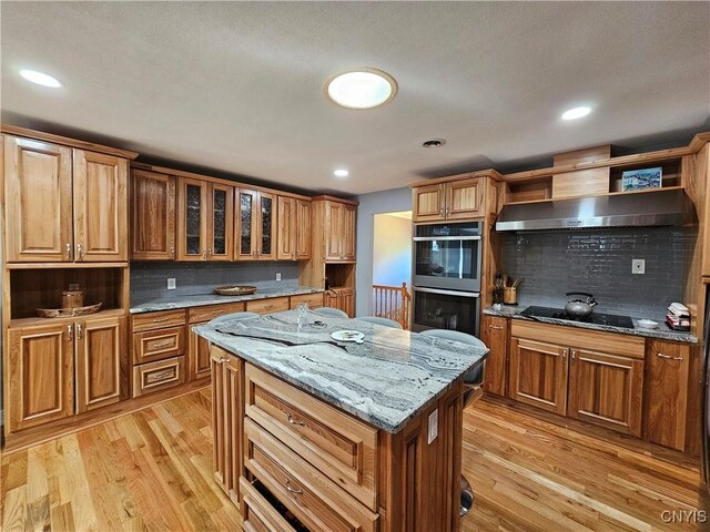 5813 Grace Rd, Deerfield, NY 13502 - kitchen featuring black electric cooktop, wall chimney exhaust hood, light wood-type flooring, decorative backsplash, and double oven