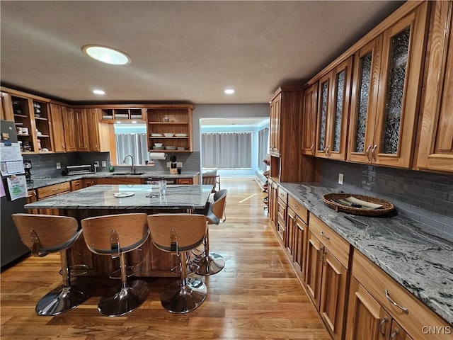5813 Grace Rd, Deerfield, NY 13502 - kitchen with open shelves, a sink, a breakfast bar area, backsplash, and freestanding refrigerator