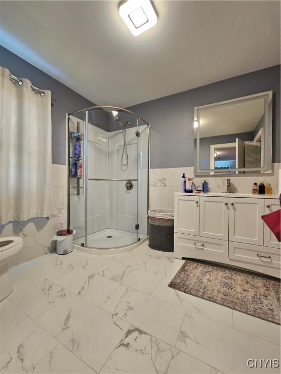 5813 Grace Rd, Deerfield, NY 13502 - full bath with marble look tile flooring, a wainscoted wall, a shower stall, vanity, and toilet