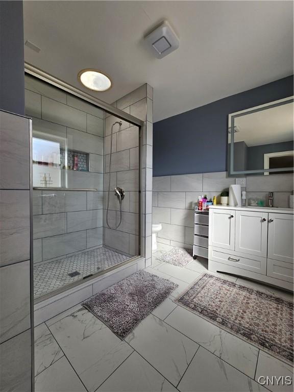 5813 Grace Rd, Deerfield, NY 13502 - full bathroom featuring tile walls, marble finish flooring, a shower stall, vanity, and toilet