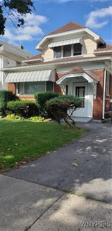 view of front of home with brick siding and a front lawn