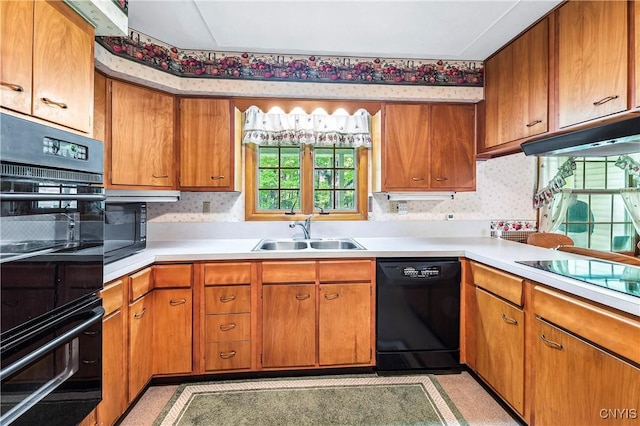 kitchen with black appliances, a sink, wallpapered walls, light countertops, and brown cabinets