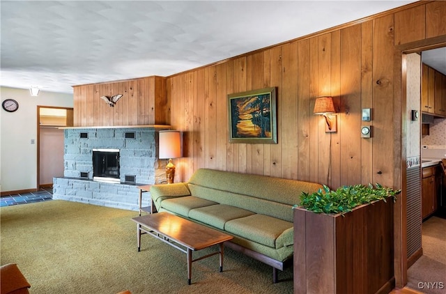 carpeted living room featuring wood walls, a stone fireplace, and baseboards