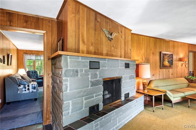 living area with wooden walls, a fireplace, carpet flooring, and ornamental molding