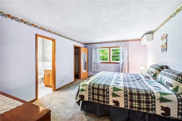 bedroom featuring a wall mounted AC, light colored carpet, baseboards, and ensuite bathroom