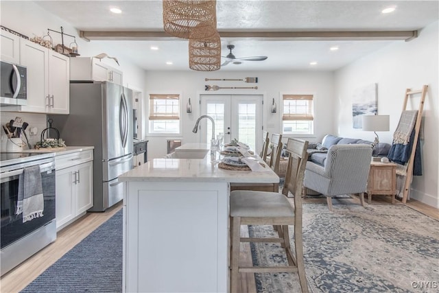 26618 Three Mile Point Rd, Lyme, NY 13622 - kitchen with stainless steel appliances, a sink, a breakfast bar, beam ceiling, and light wood-style flooring