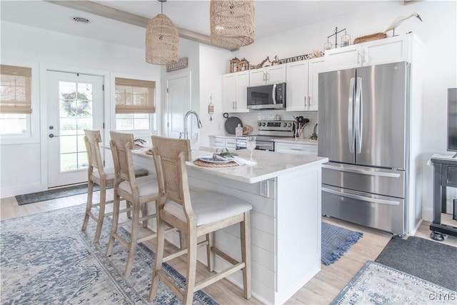 26618 Three Mile Point Rd, Lyme, NY 13622 - kitchen featuring stainless steel appliances, light wood-style floors, a breakfast bar area, and plenty of natural light