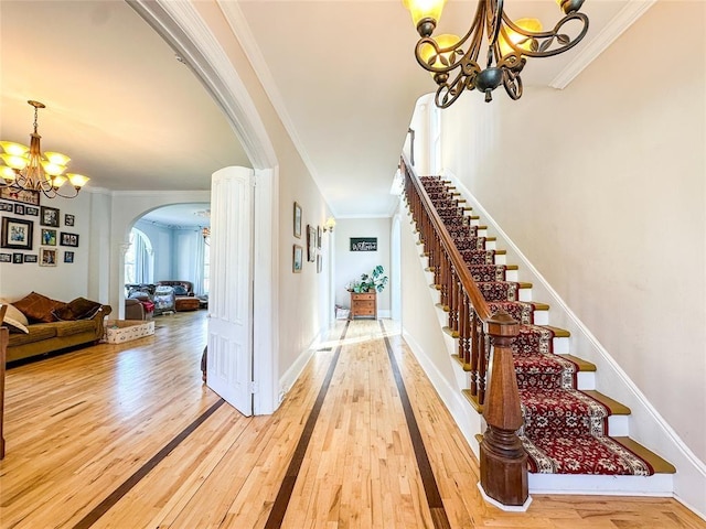 442 Front St, Owego, NY 13827 - staircase featuring arched walkways, a chandelier, hardwood / wood-style floors, and crown molding