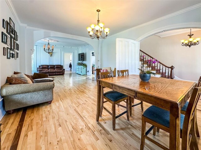 442 Front St, Owego, NY 13827 - dining space featuring a chandelier, arched walkways, light wood-style floors, crown molding, and stairs