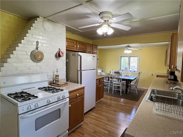2055 Fitzgerald Pt S, Otisco, NY 13110 - kitchen with white appliances, ceiling fan, brown cabinetry, light countertops, and dark wood-style flooring