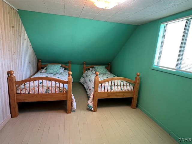 bedroom with hardwood / wood-style flooring, baseboards, and lofted ceiling