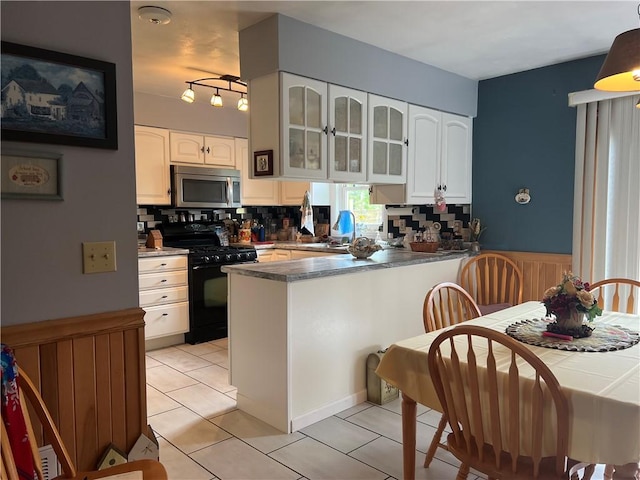 427 Church St, Winfield, NY 13491 - kitchen with gas stove, stainless steel microwave, tasteful backsplash, white cabinets, and wainscoting