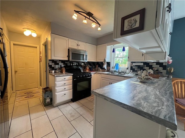 427 Church St, Winfield, NY 13491 - kitchen featuring black range with gas stovetop, stainless steel microwave, backsplash, white cabinetry, and a peninsula