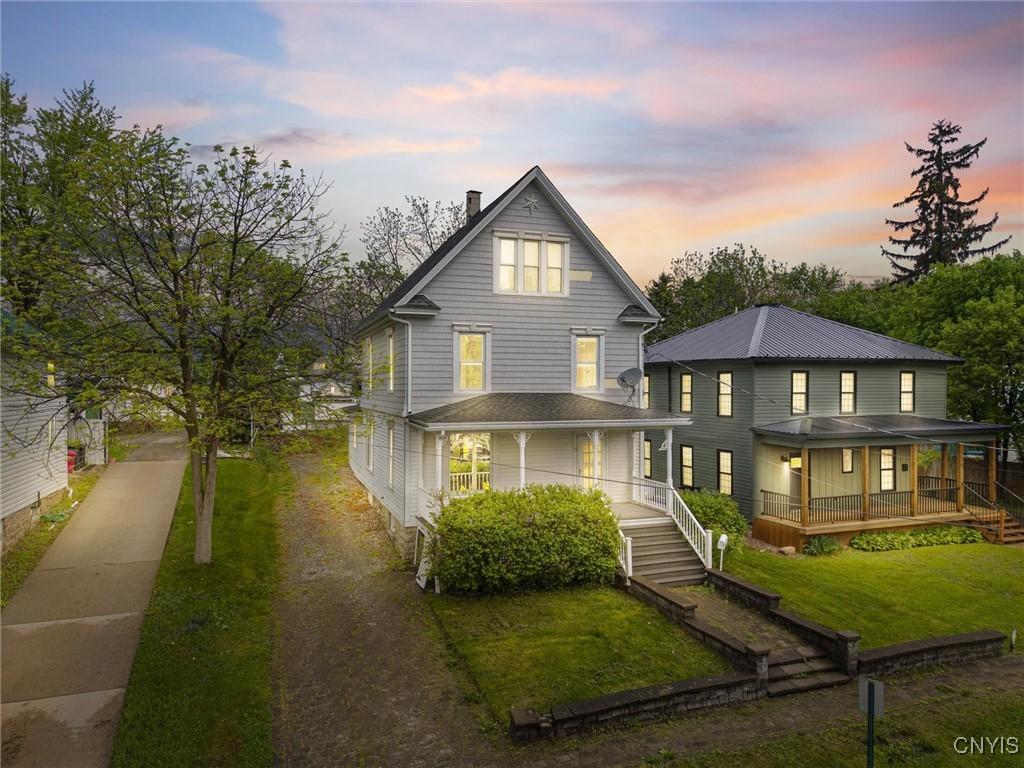 8 Washington St, Alexandria, NY 13607 - back of property at dusk with a porch, a lawn, a chimney, and driveway