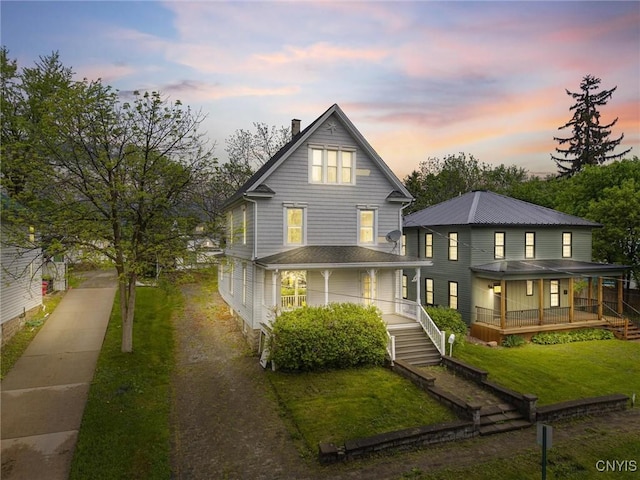 8 Washington St, Alexandria, NY 13607 - back of property at dusk with a porch, a lawn, a chimney, and driveway
