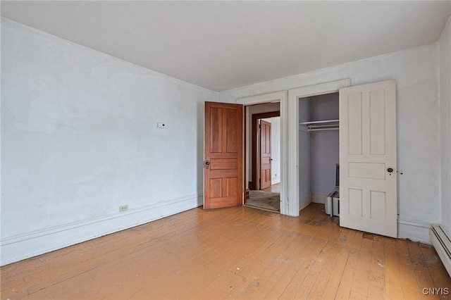 8 Washington St, Alexandria, NY 13607 - unfurnished bedroom with light wood finished floors, a closet, a baseboard radiator, baseboards, and a baseboard heating unit