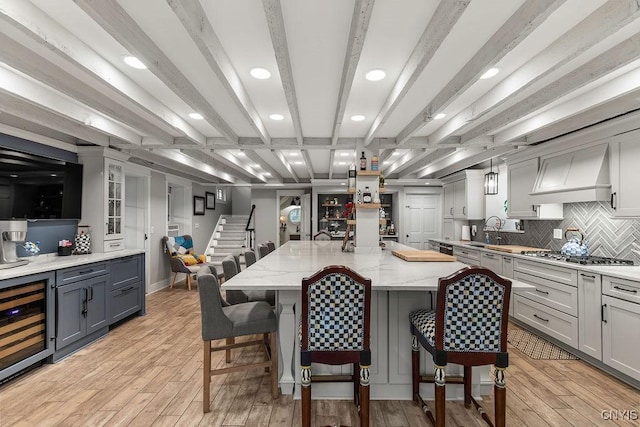 3721 Cold Springs Rd, Lysander, NY 13027 - kitchen featuring beverage cooler, light wood finished floors, stainless steel gas cooktop, light stone countertops, and backsplash