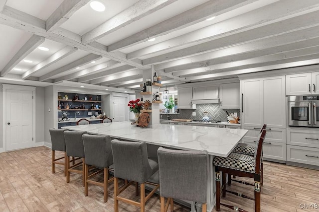 3721 Cold Springs Rd, Lysander, NY 13027 - kitchen with stainless steel appliances, beam ceiling, a spacious island, light stone countertops, and light wood finished floors