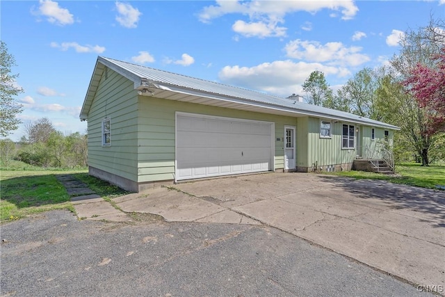 single story home with metal roof, concrete driveway, and an attached garage