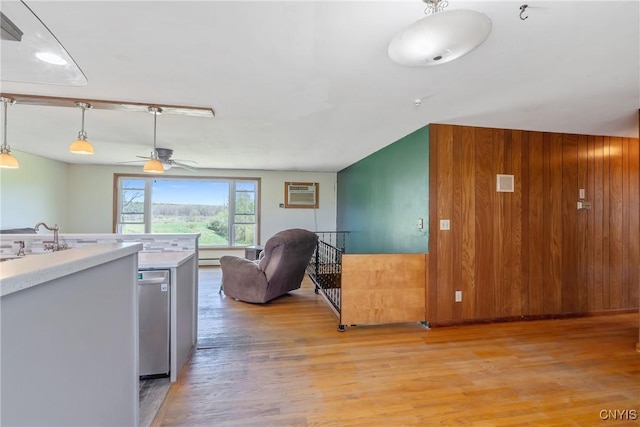 kitchen featuring a ceiling fan, light wood finished floors, a sink, light countertops, and decorative light fixtures