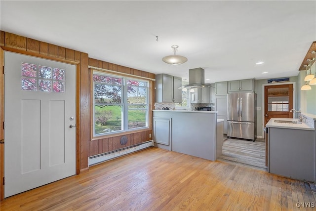 kitchen featuring freestanding refrigerator, a baseboard radiator, island exhaust hood, gray cabinetry, and light wood-style flooring