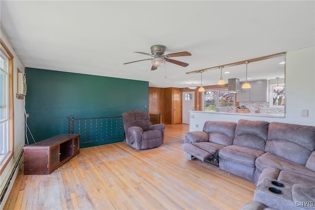 living area with light wood-type flooring, baseboard heating, and ceiling fan