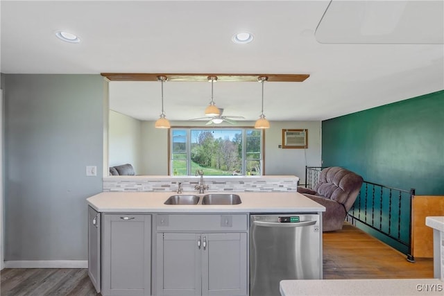 kitchen featuring stainless steel dishwasher, a sink, open floor plan, wood finished floors, and light countertops