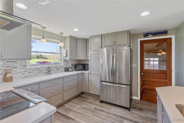 kitchen featuring stainless steel refrigerator, black microwave, gray cabinetry, light wood-type flooring, and backsplash