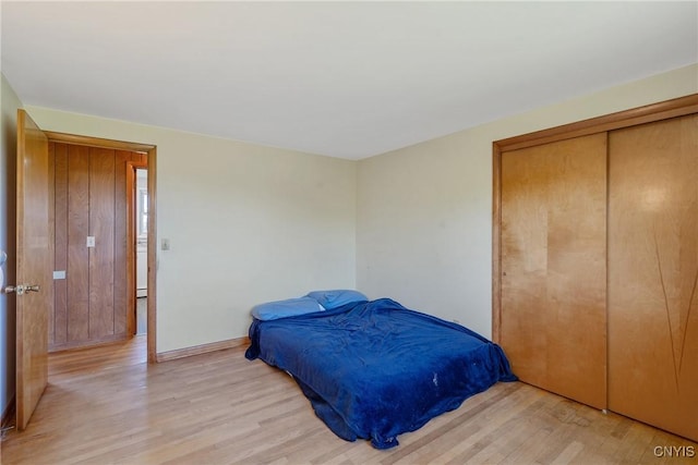 bedroom featuring light wood-style floors, a closet, and baseboards