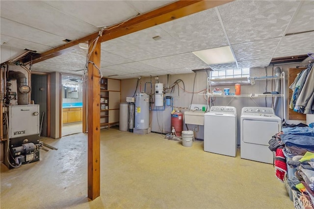 below grade area featuring washer and dryer, water heater, a paneled ceiling, a central vacuum unit, and a water softener system