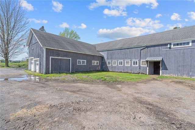 view of property with dirt driveway, a barn, and a garage
