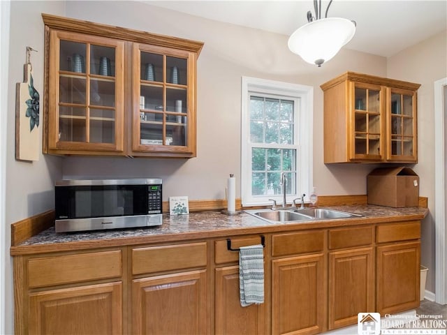 474 Fairmount Ave, Ellicott, NY 14701 - kitchen featuring stainless steel microwave, a sink, glass insert cabinets, brown cabinetry, and decorative light fixtures