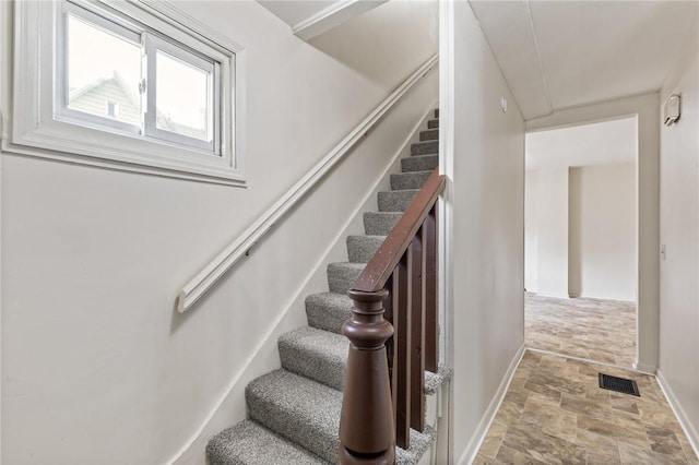 staircase with stone finish flooring, attic access, and baseboards