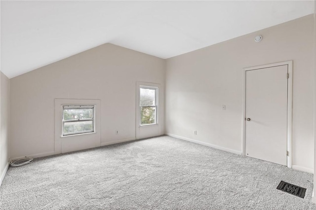 empty room featuring carpet flooring, vaulted ceiling, and baseboards