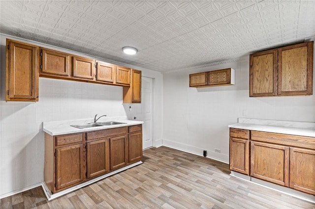 kitchen featuring brown cabinetry, light countertops, light wood-type flooring, and an ornate ceiling