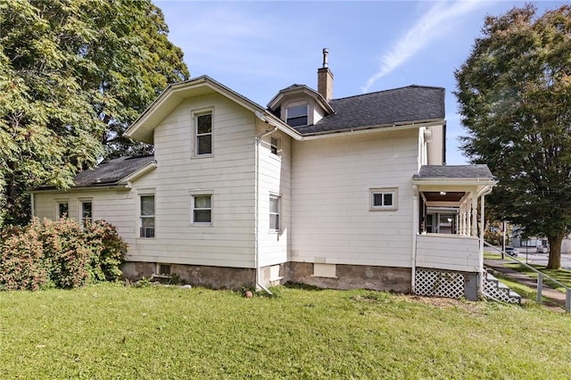 rear view of house featuring a chimney and a yard