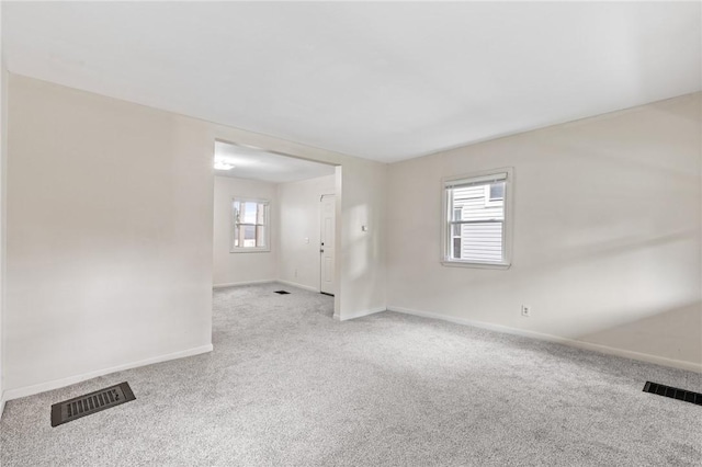 carpeted spare room featuring healthy amount of natural light and baseboards