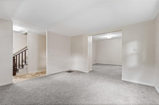 spare room featuring carpet, baseboards, and stairs