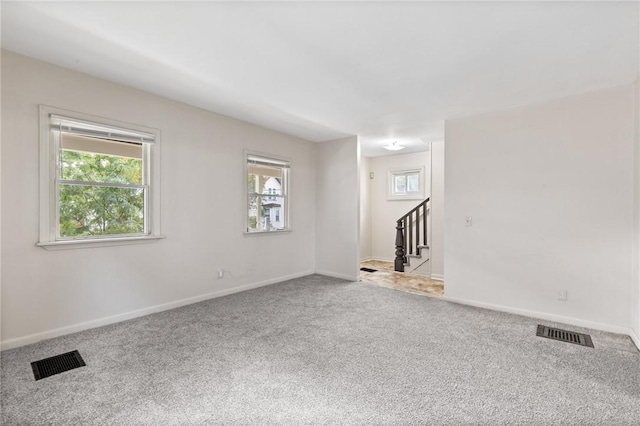 spare room featuring carpet flooring, stairs, and baseboards