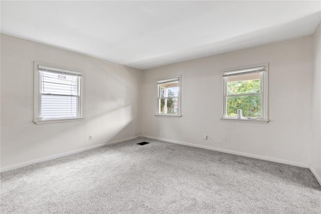 unfurnished room with healthy amount of natural light, carpet flooring, and baseboards