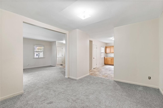 unfurnished room with light carpet and baseboards